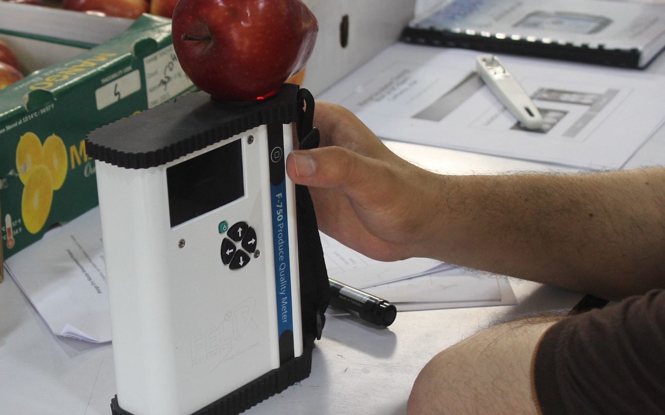 NIR device scanning an apple in a lab.